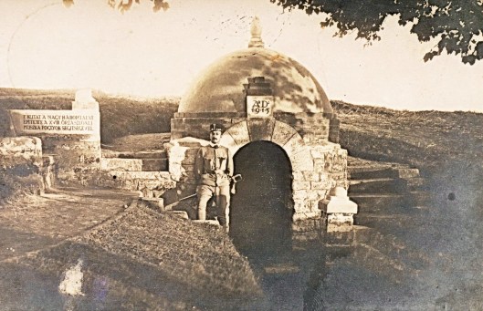 The well at Kissitke POW camp, Hungary, in 1915. The inscription on the left reads: “This well was built in the Great War by the 18th guard battalion with the help of Russian prisoners.” Béla Zombory-Moldován, camp commandant and well-creator, wears the “wretched” regulation officer’s sword that had been the bane of his life at the front.